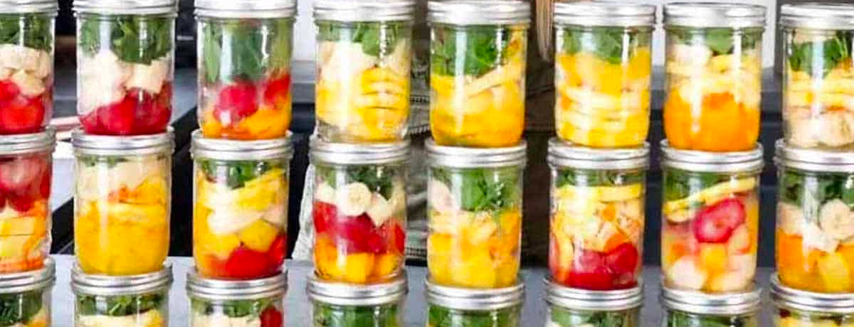 a bunch of jars stacked on each other with green smoothie ingredients on them ready to be stored in the freezer