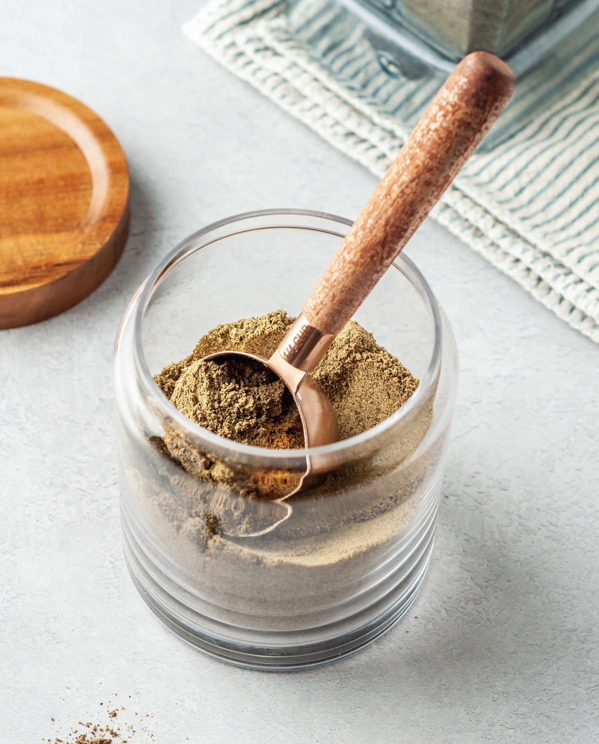 Glass jar with homemade protein powder and measuring cup.