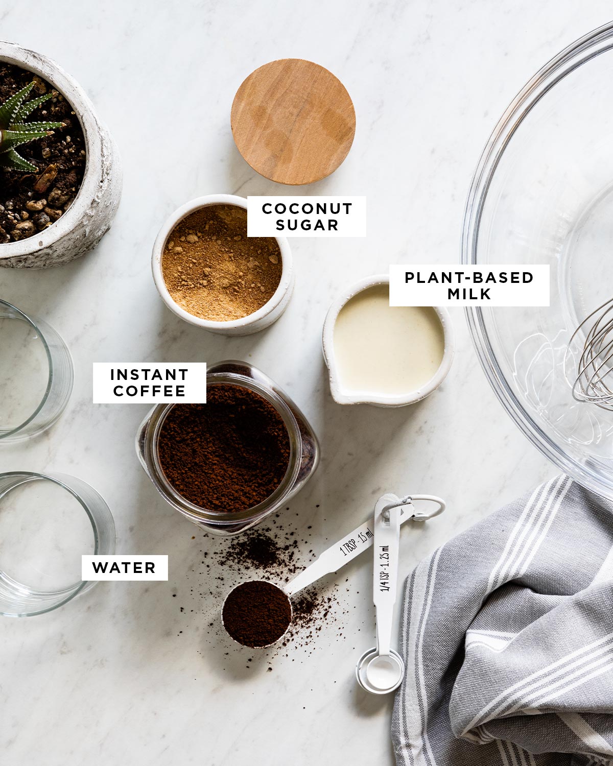 labeled ingredients for dalgona coffee recipe including coconut sugar, plant-based milk, instant coffee and water.