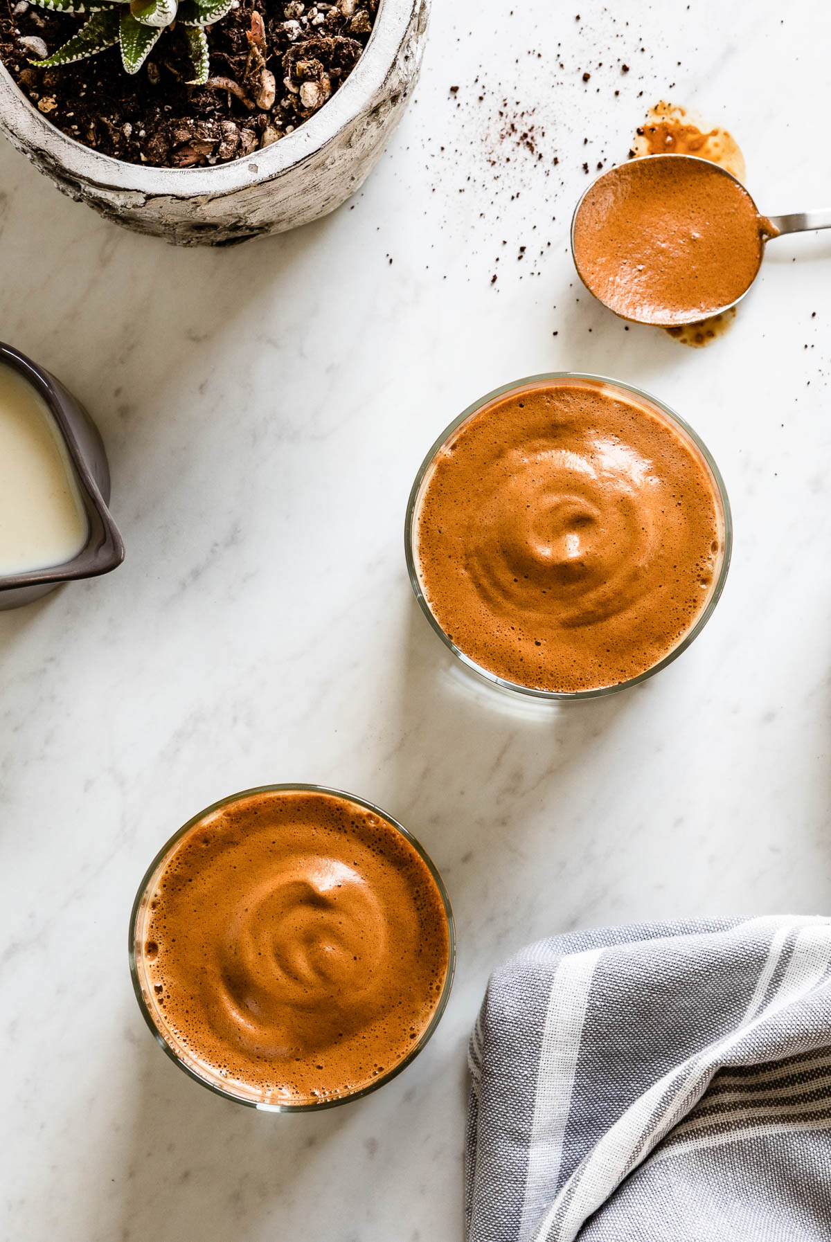 2 plant-based beverages topped with a brown whipped topping.