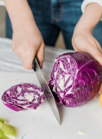 chopping a whole purple cabbage with a black chef's knife.