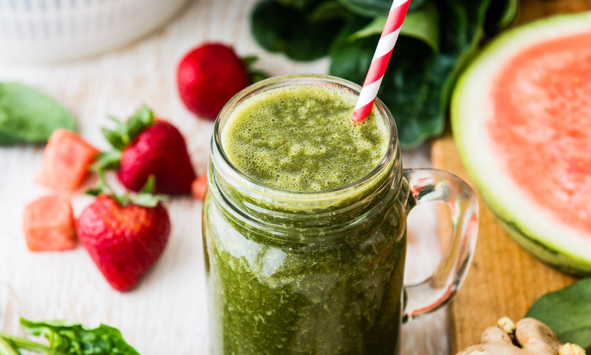 strawberry watermelon green smoothie in a glass mug with a striped paper straw.