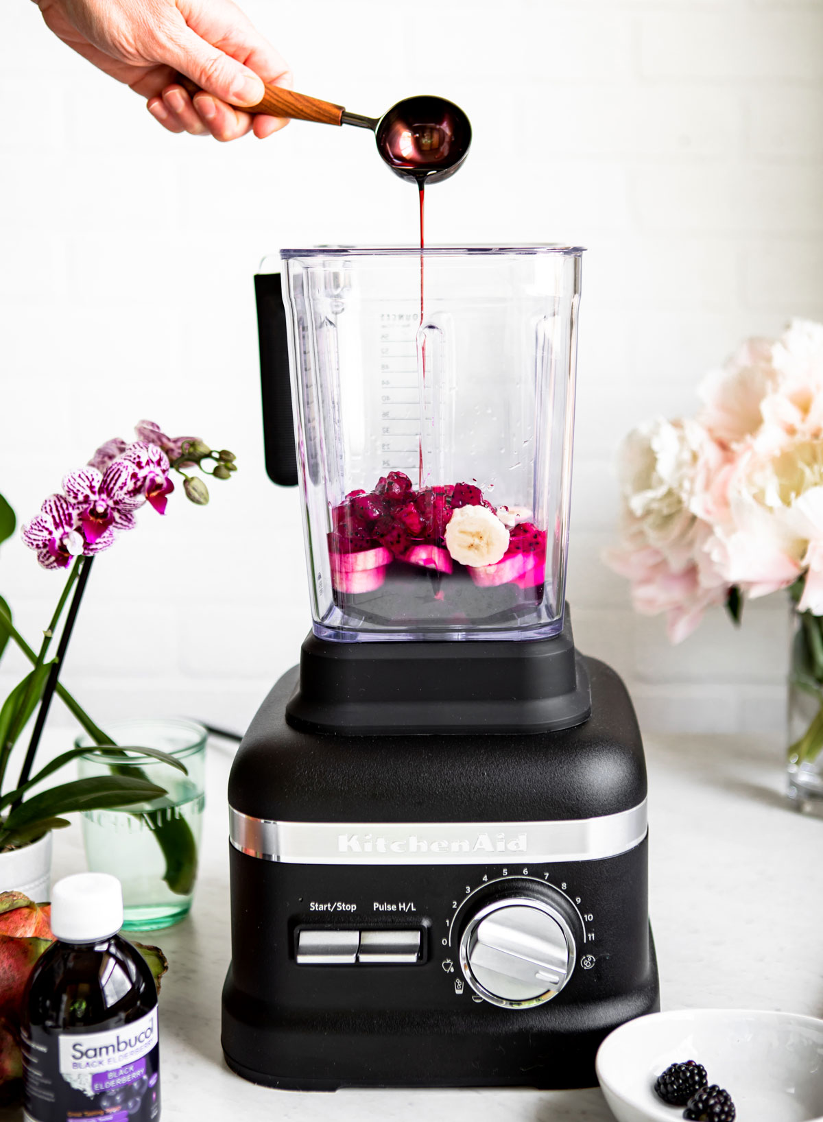 Adding elderberry syrup to a smoothie recipe.