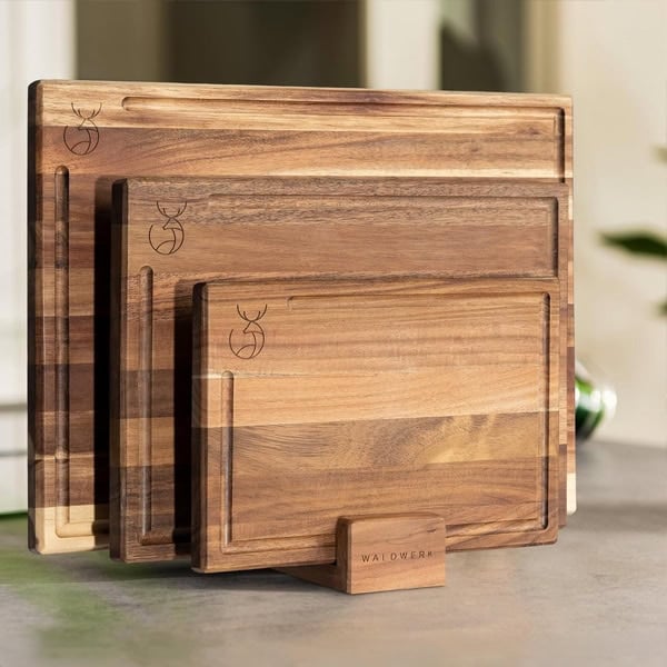 Set of four wooden cutting boards with engraved logo on a kitchen counter.