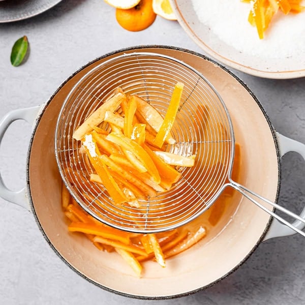 Juicing fresh oranges in a strainer for healthy smoothies or drinks.