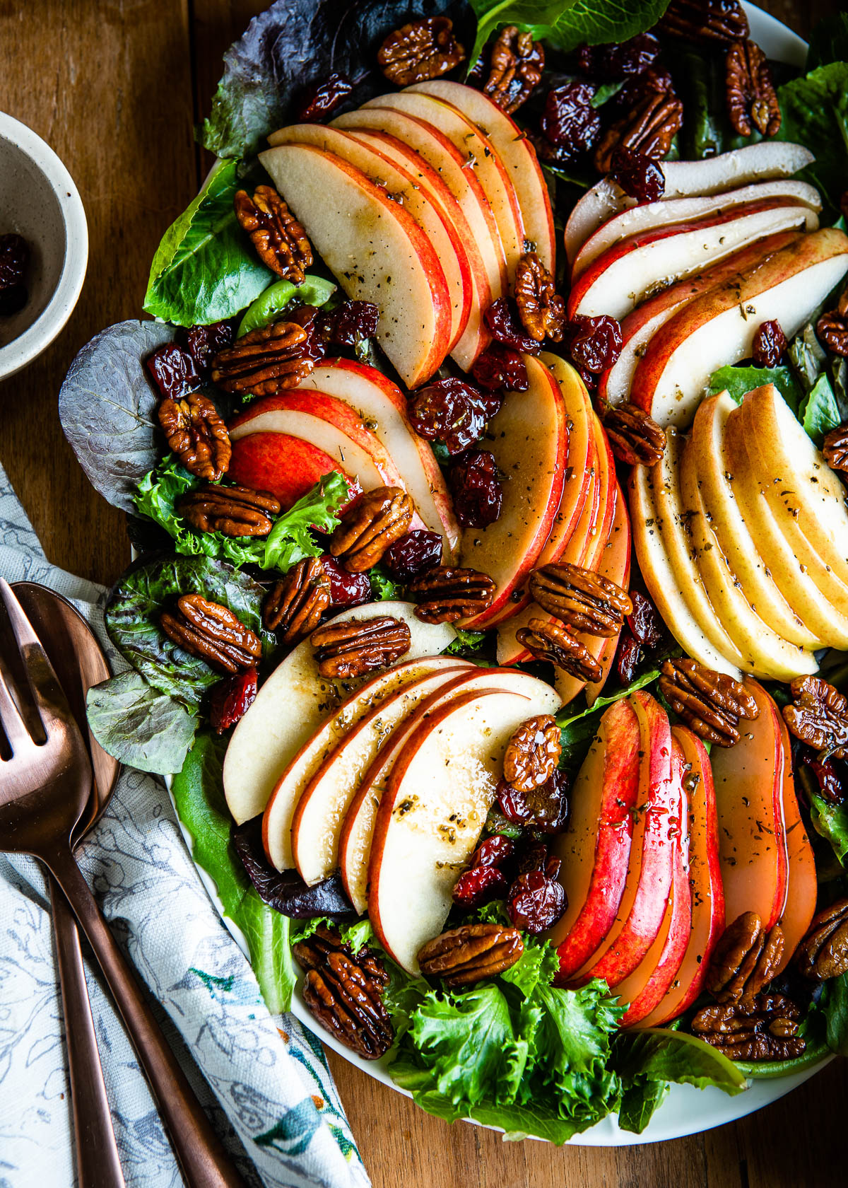sliced apples and pears sitting on a bed of mixed greens and topped with candied pecans, vinaigrette and dried cherries.