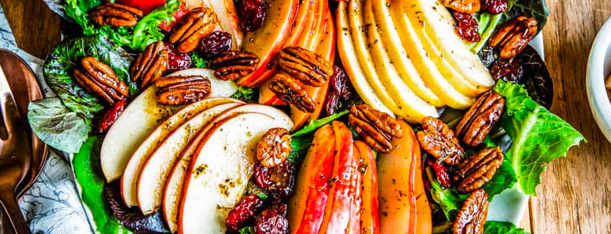 overhead shot of salad with sliced apples, candied pecans, and more