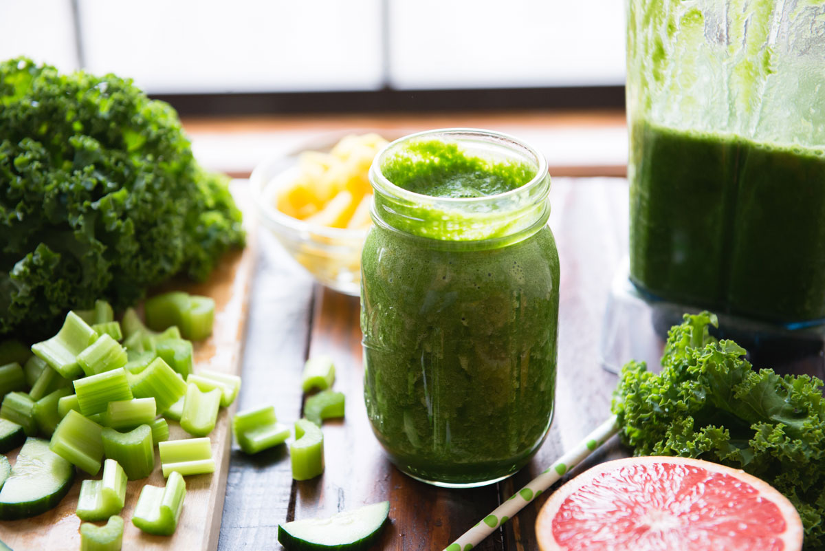 Green fat-burning smoothie for weight loss surrounded by healthy ingredients.