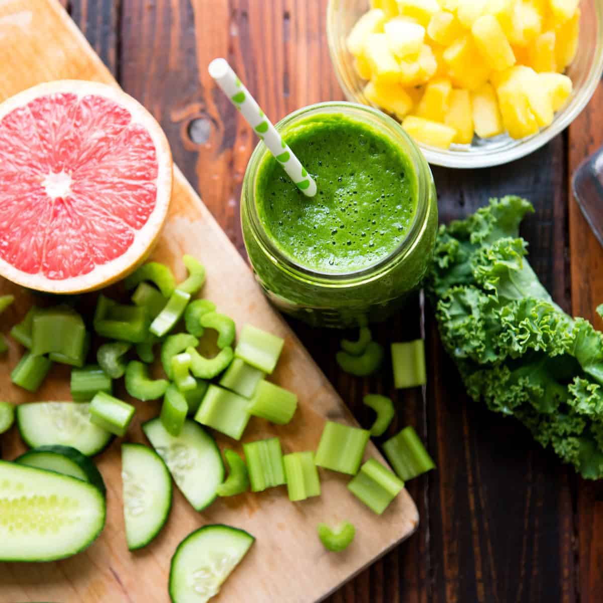 Glass of fat-burning smoothie surrounded by fruits and vegetables.
