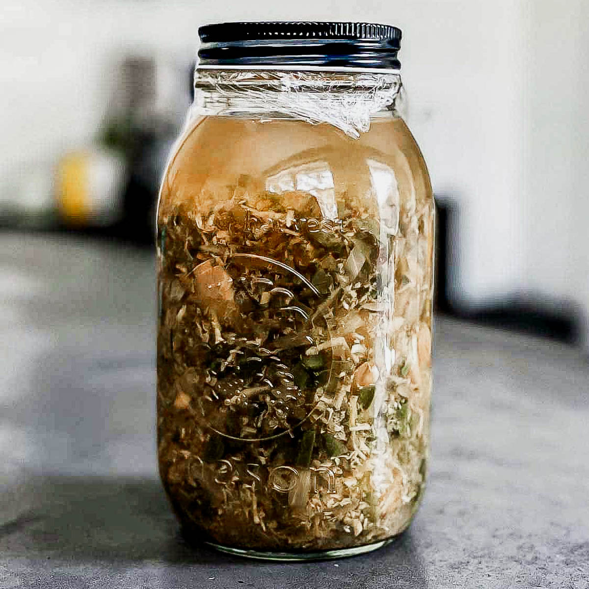 Glass jar of fir cider with a black top.