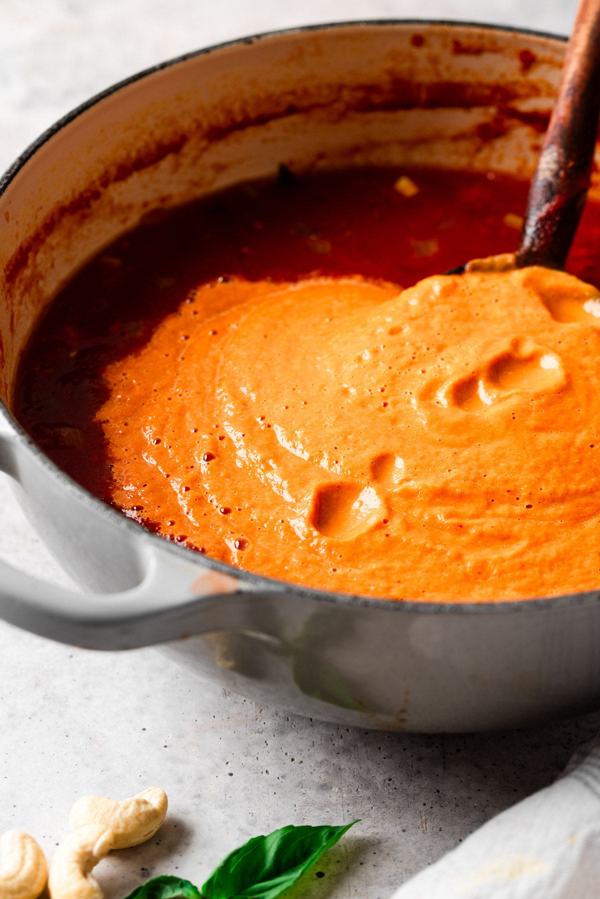 Stirring cashews into soup with a wooden spoon.