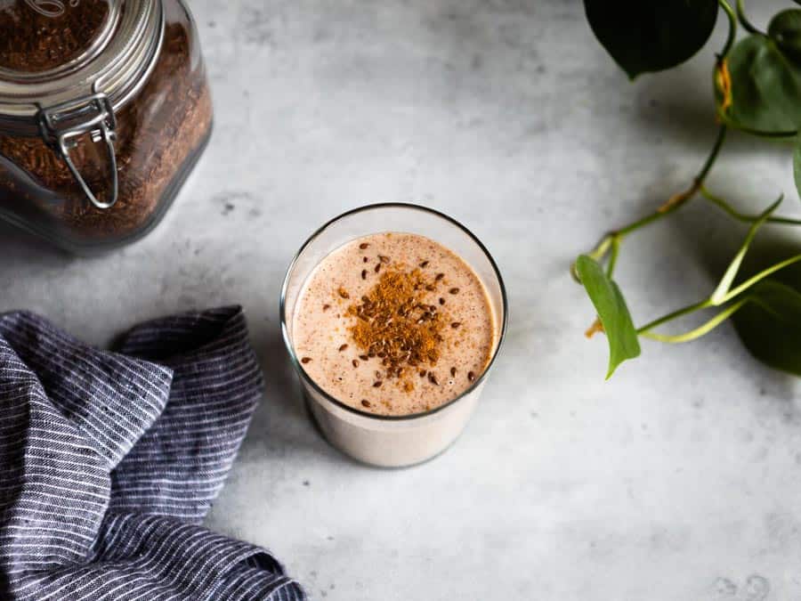 flaxseed smoothie in a glass topped with flaxseed and cinnamon.