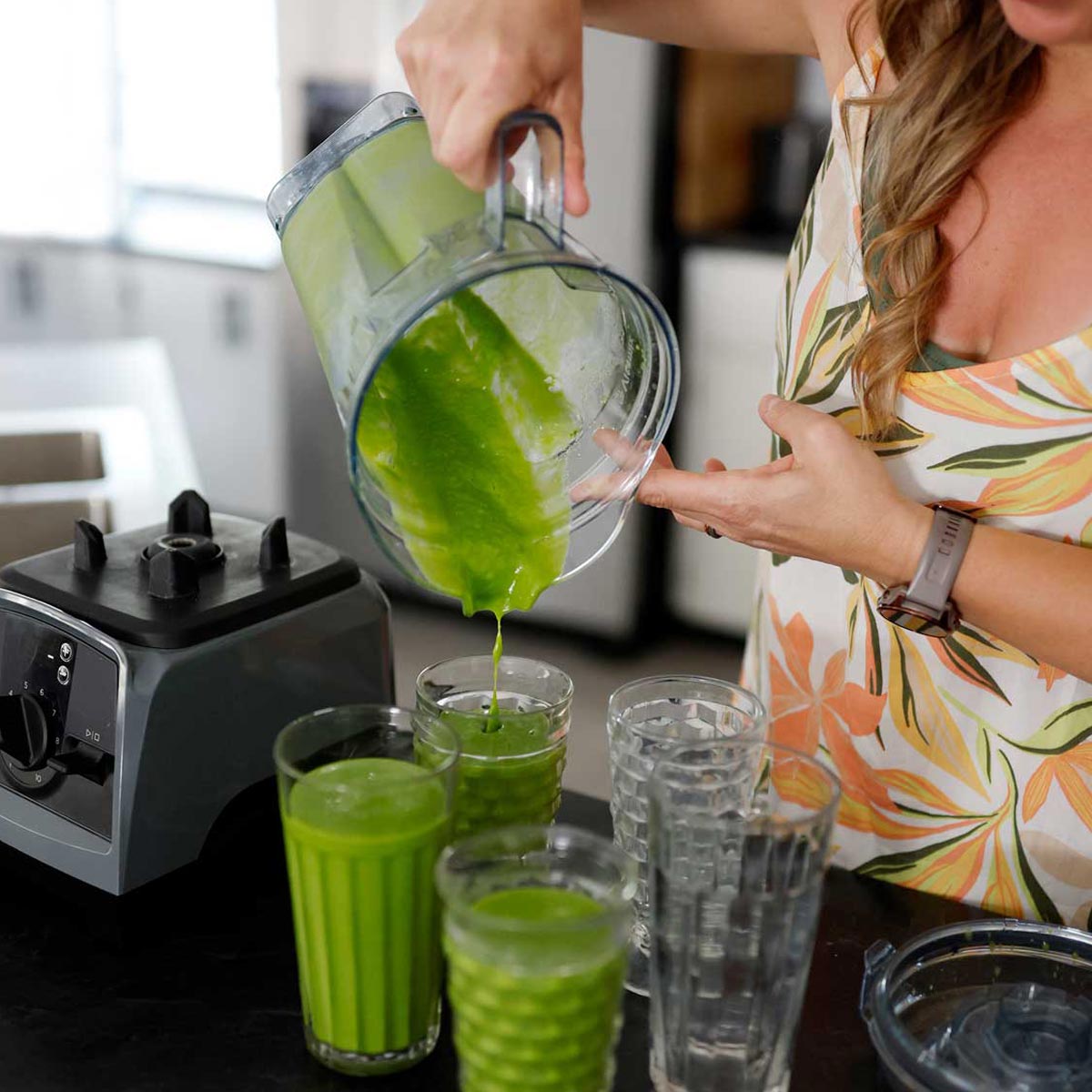 Woman pouring smoothies into glass cups
