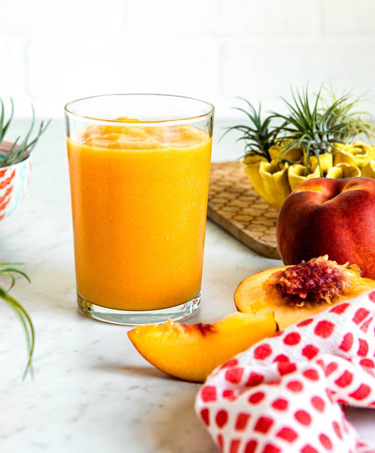 summer orange smoothie in a glass on a white countertop.