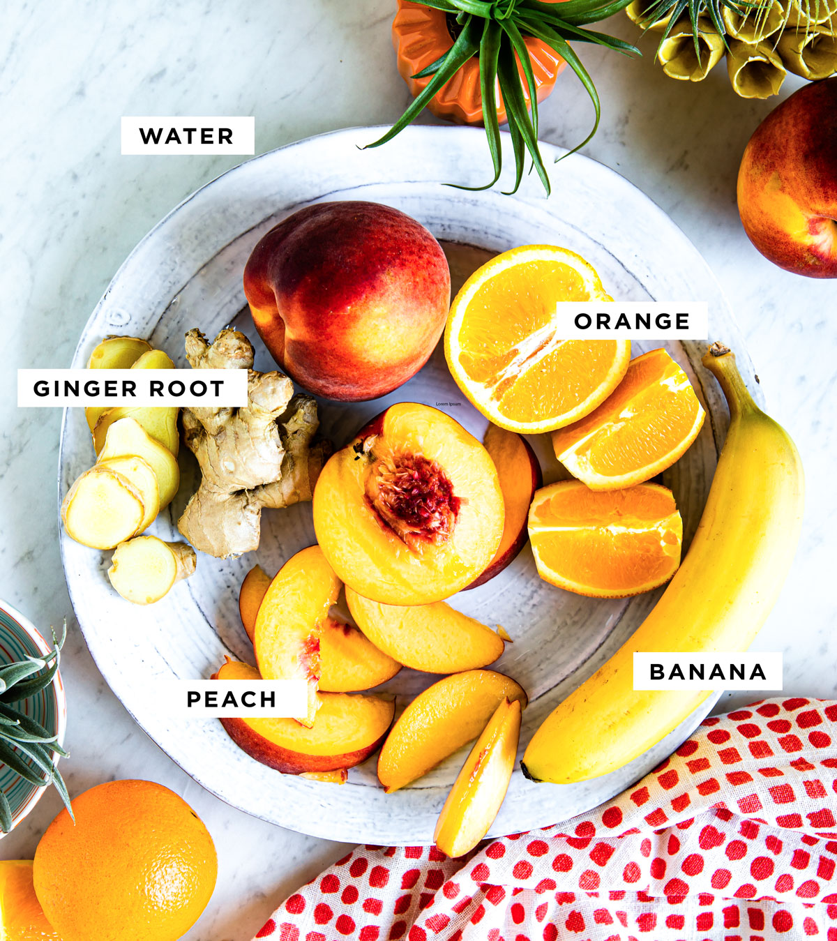 labeled ingredients to make a peach smoothie including orange, ginger root, peach and banana.