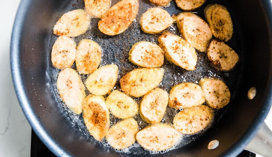 plantains frying in coconut oil in a skillet.