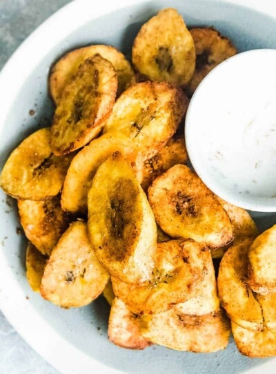 fried plantains on a plate with a bowl of dipping sauce.