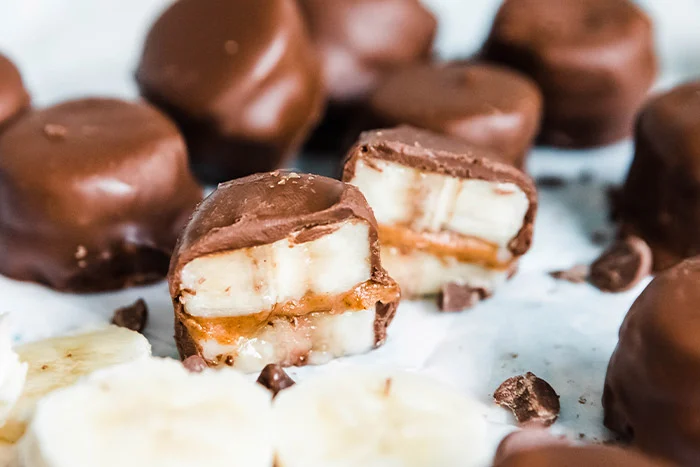 Dip the frozen banana sandwiches in the chocolate