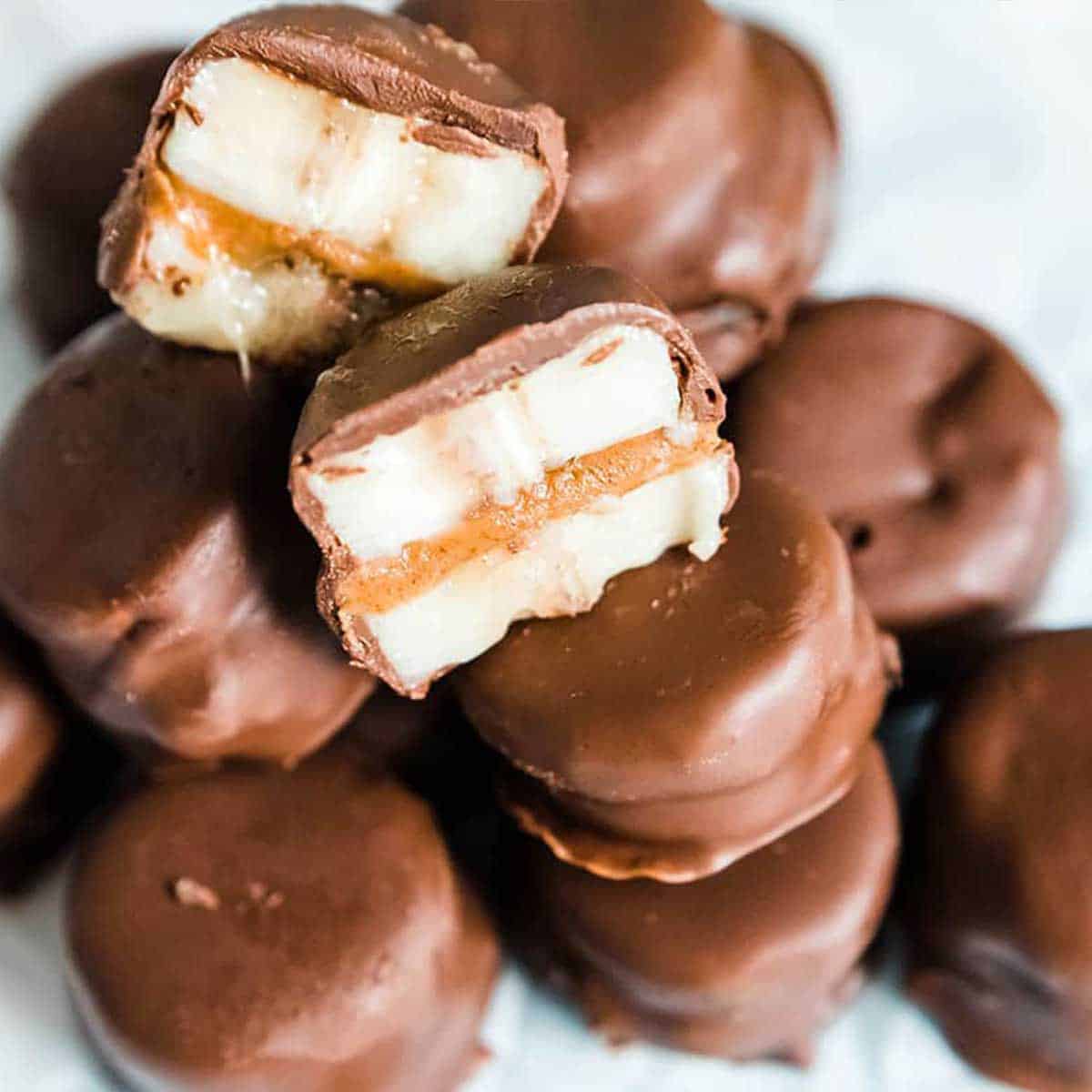 Frozen chocolate covered banana bites stacked on plate.