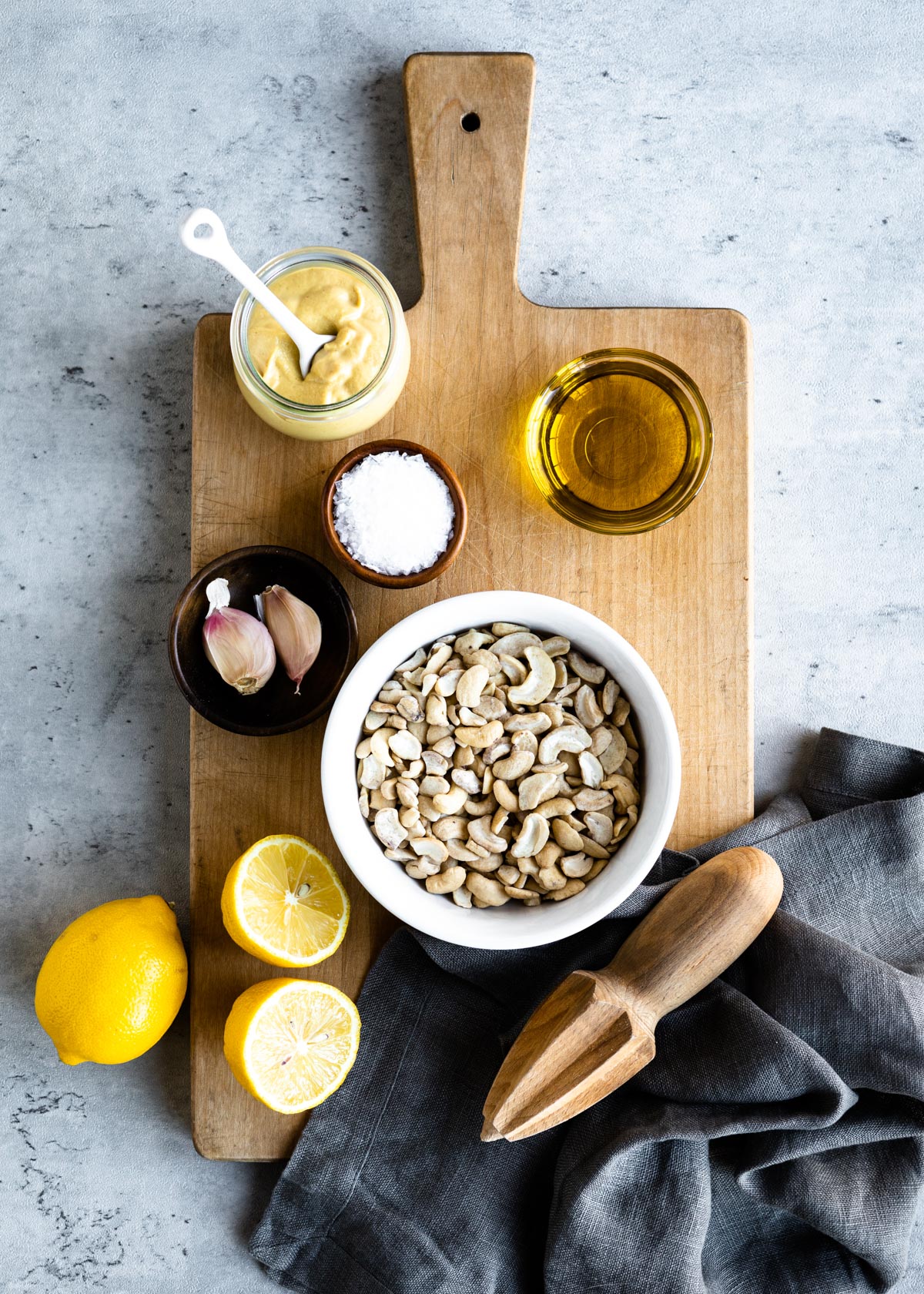 ingredients for vegan aioli including olive oil, sea salt, garlic cloves, raw cashews and lemons.