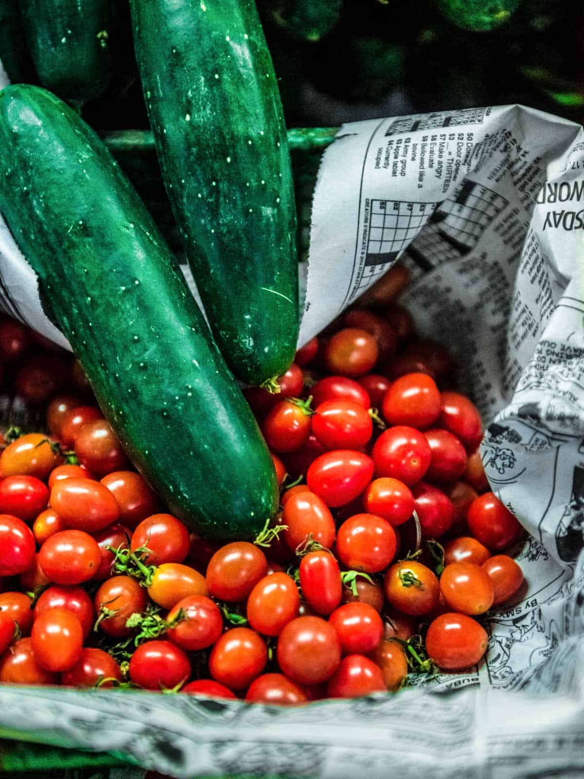 cucumbers and cherry tomatoes in newspaper.