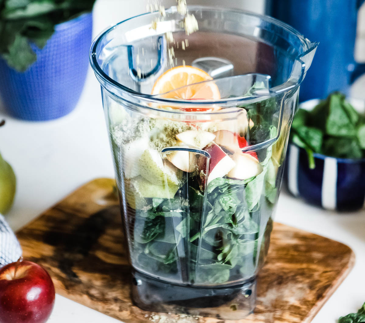 glowing green smoothie ingredients in a blender container.