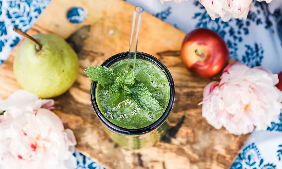 kimberly snyder smoothie recipe in a glass topped with mint and a glass straw.