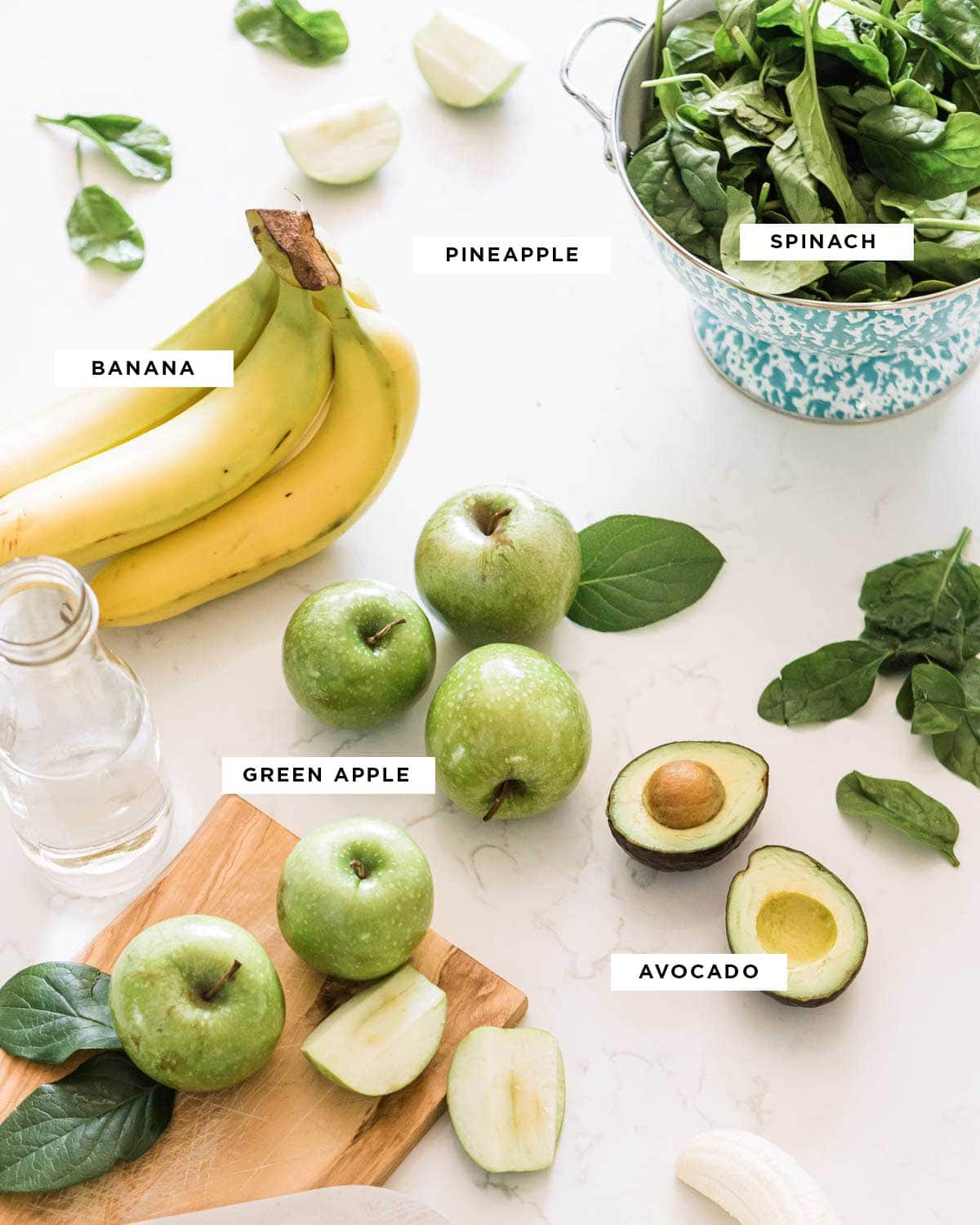 ingredients for an apple smoothie including spinach, pineapple, banana, green apple and avocado.