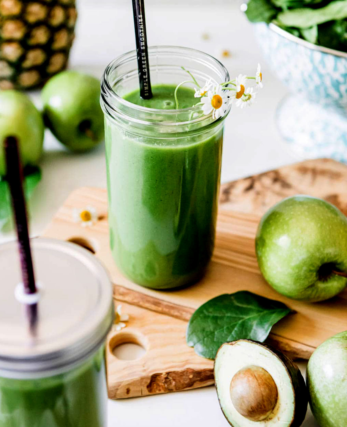 Green apple smoothie in a glass jar with avocado, spinach, and apples, surrounded by fresh ingredients for a healthy green smoothie recipe.