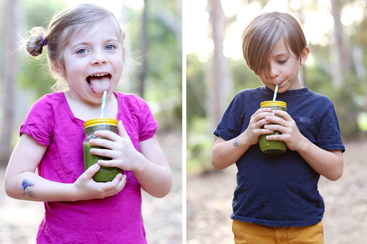 children drinking green smoothies in mason jars with metal straws
