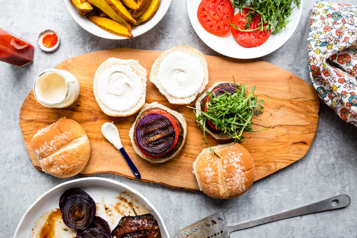 overhead view of grilled vegan burgers with fresh toppings on a wooden board