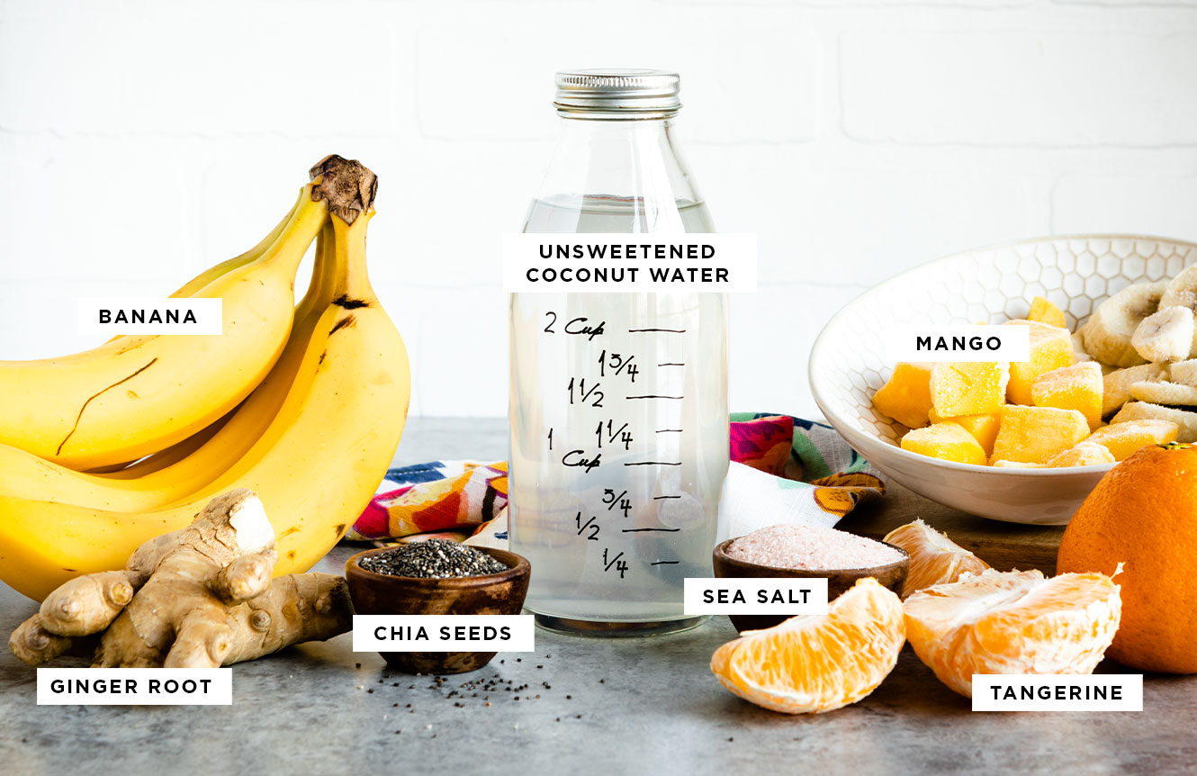 labeled ingredients for a hangover cure drink including unsweetened coconut water, mango, tangerine, sea salt, chia seeds, ginger root and banana.