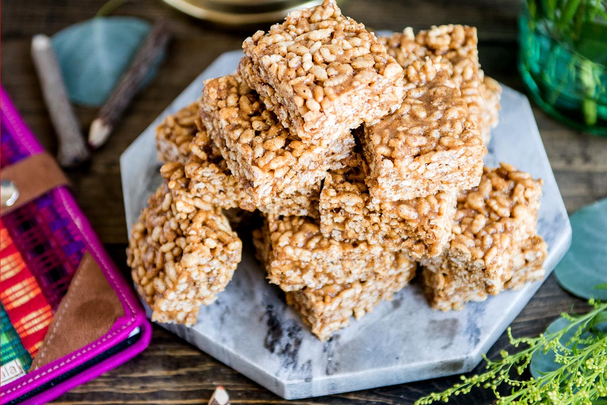 stack of rice krispie treats on a marple plate with fresh bouquet on table.