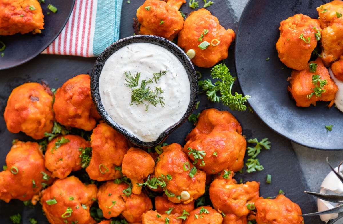 serving buffalo cauliflower bites as an easy BBQ side with a vegan ranch dipping sauce in the center.