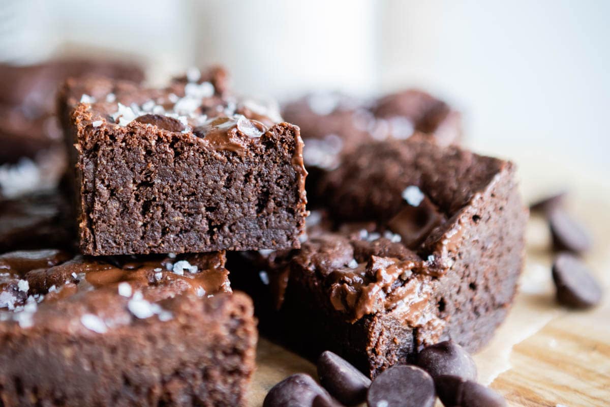 stacked fudgy brownies on a wooden tray.