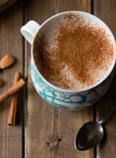 warm almond milk in a mug with cinnamon on top showing a healthy caffeine alternative.