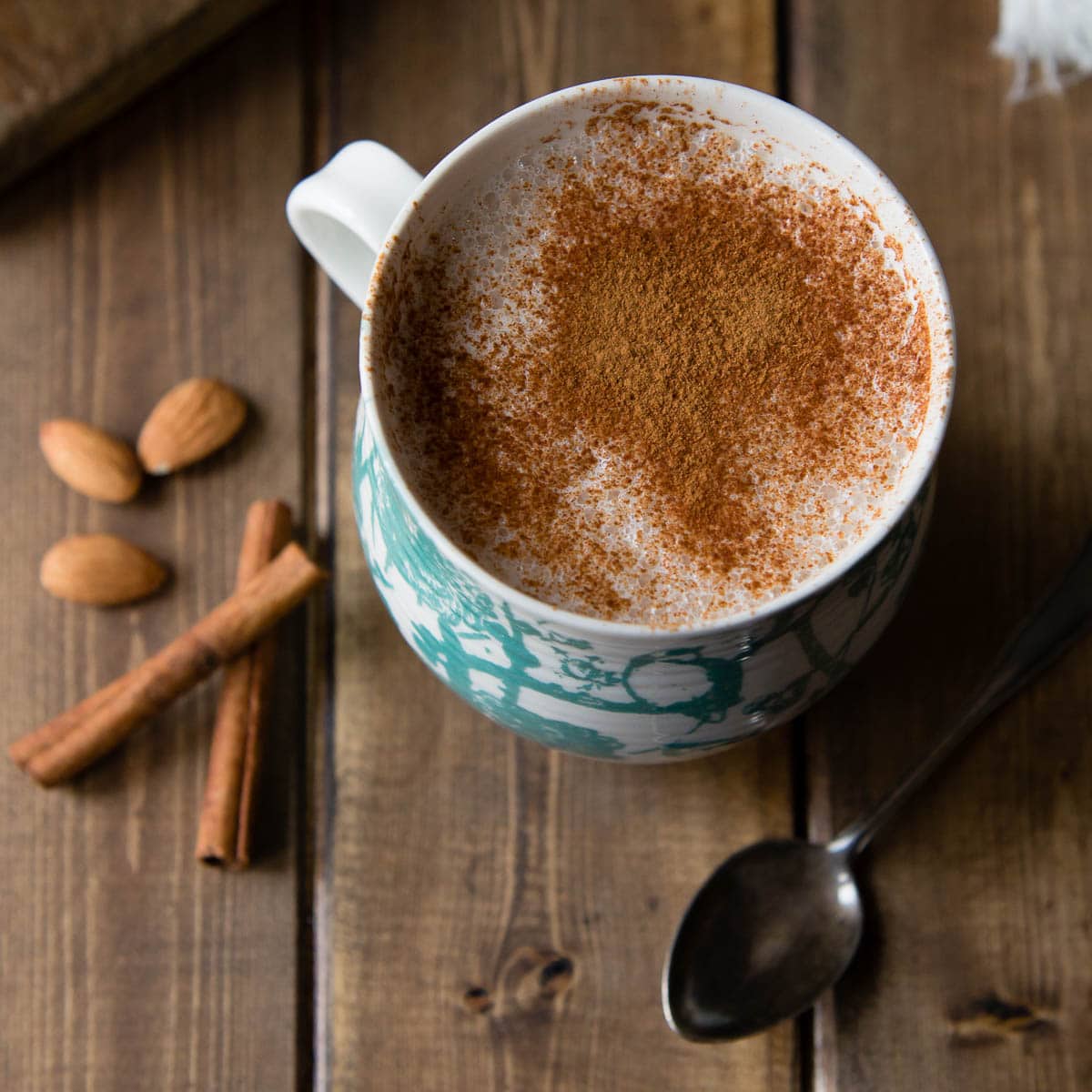overhead photo of warm almond milk in a mug with cinnamon on top showing a healthy caffeine alternative
