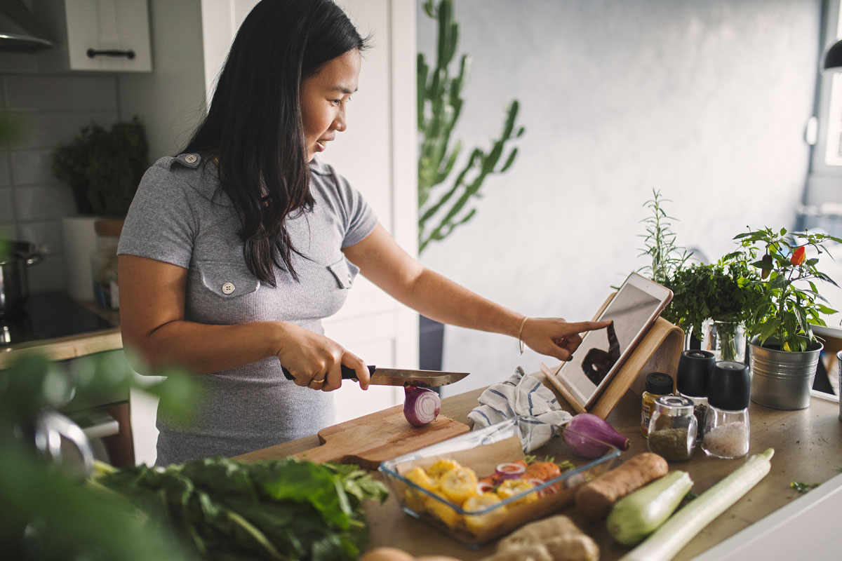 Person using fall menu on iPad to make meal plan recipes in kitchen.