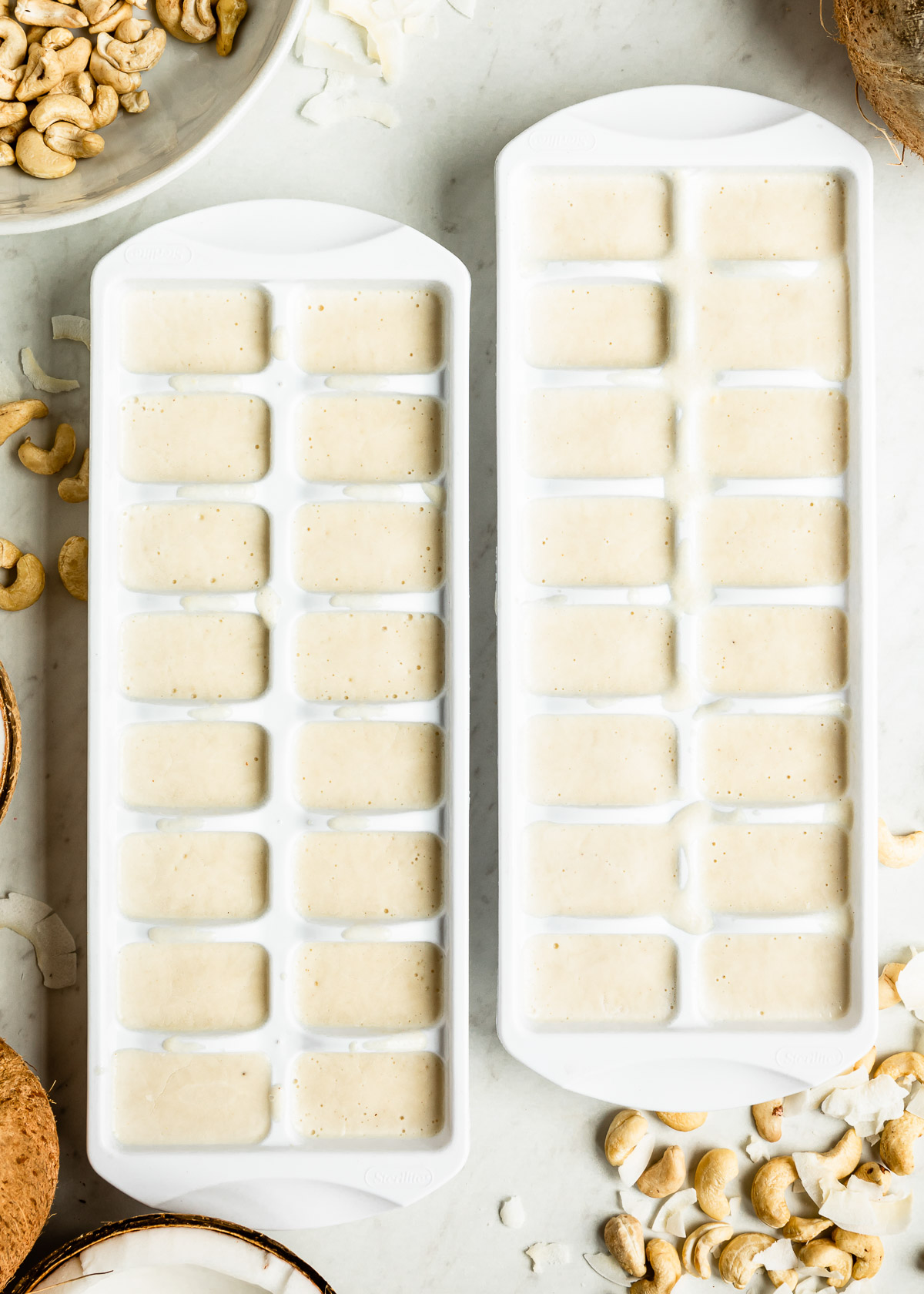 Two ice cube trays filled with freshly frozen healthy fats smoothie cubes.