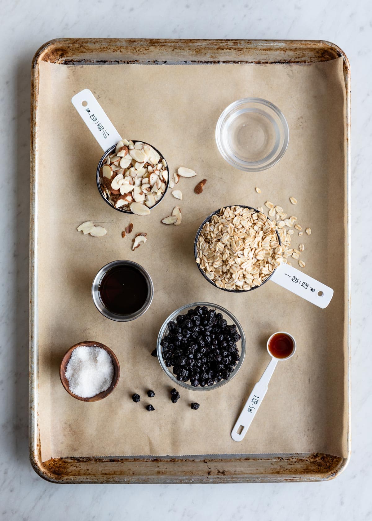 ingredients for gluten-free snack including coconut oil, sliced almonds, rolled oats, maple syrup, dried blueberries, sea salt and vanilla.