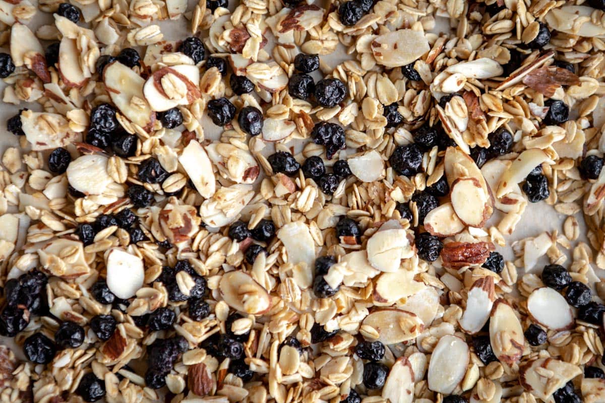 healthy granola recipe spread out on a parchment lined baking sheet.