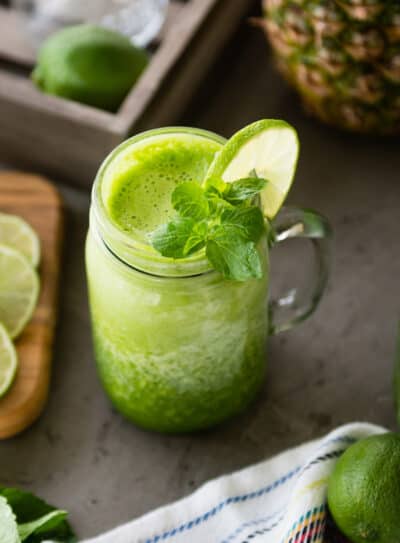 Refreshing green smoothie with lime and mint in a mason jar on a kitchen counter.