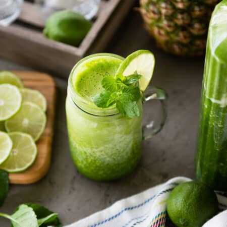 Refreshing green smoothie with lime and mint in a mason jar on a kitchen counter.