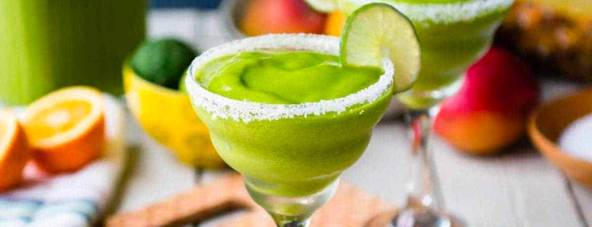 green smoothie in a margarita glass with salt on the rim and a lime wedge