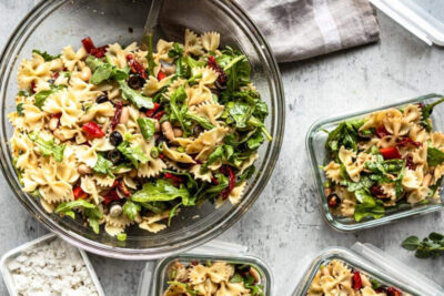 Healthy pasta salad in bowl with meal prep containers.