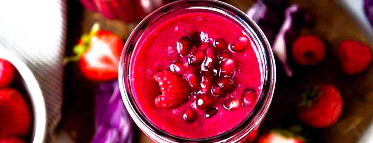 bright pink/red smoothie with pomegranate arils on top
