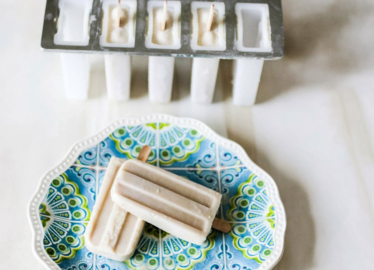 coconut popsicles on plate with extra popsicles in the background