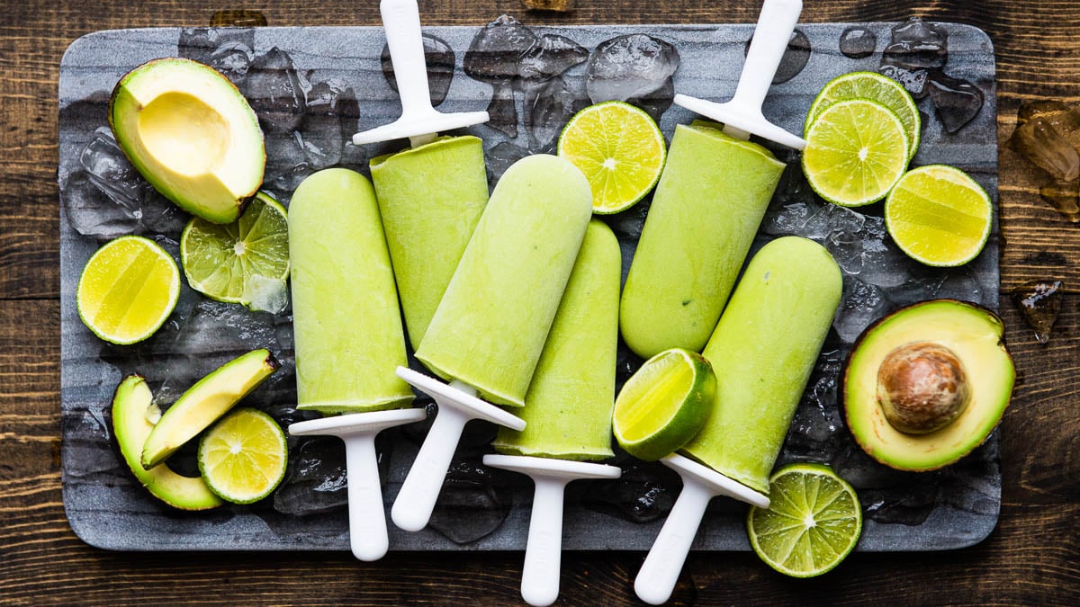 Healthy popsicles on a board with lime and avocado