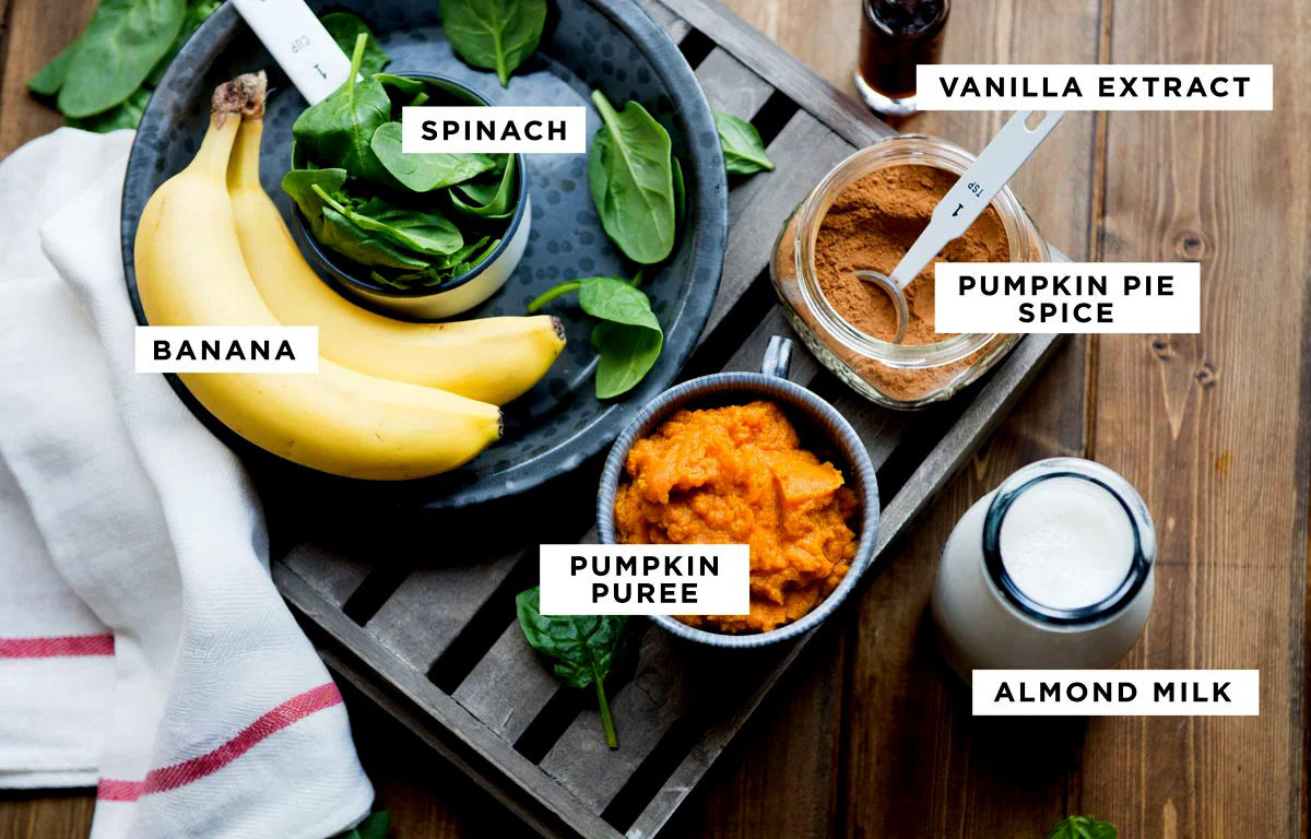 Ingredients for a pumpkin smoothie recipe in bowls on wooden table.