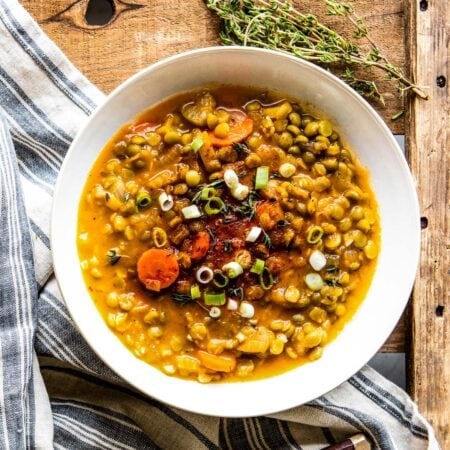 A bowl of healthy lentil soup with vegetables and green onions.